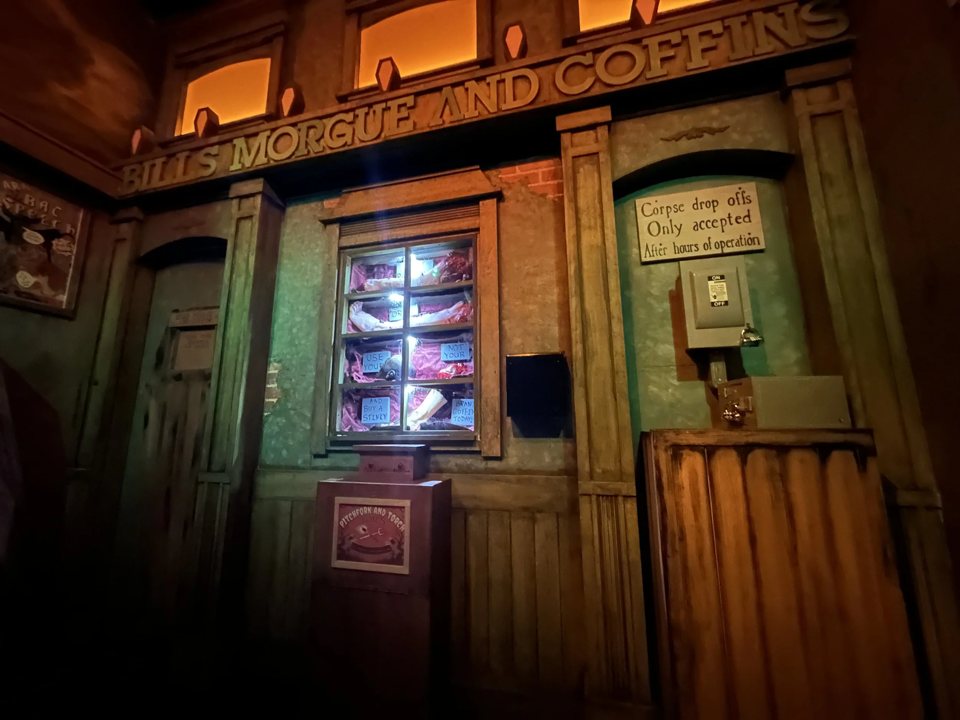 Régi westernes homlokzat „Bill's Morgue and Coffins” felirattal és kivilágított kirakattal