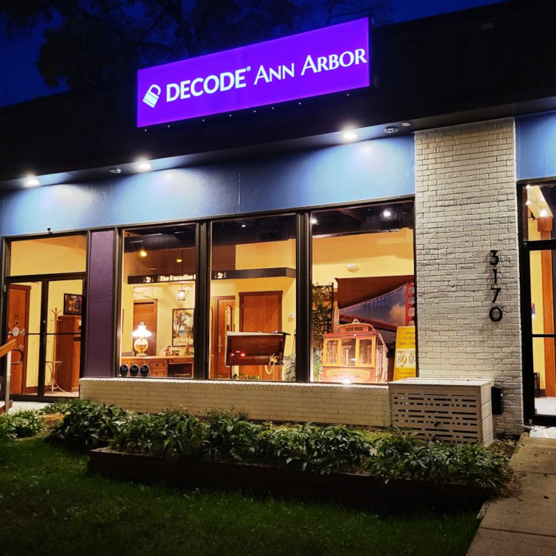 Az esti, kivilágított üzlethomlokzat lila Decode Ann Arbor felirattal