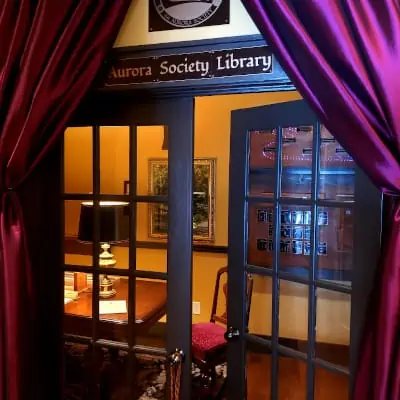 Bíborfüggönyök között üvegezett ajtó nyílik az Aurora Society Library szobába