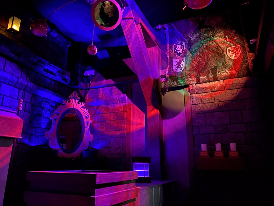 Castle room in blue and red light with an ornate mirror, a heraldic tapestry and candles