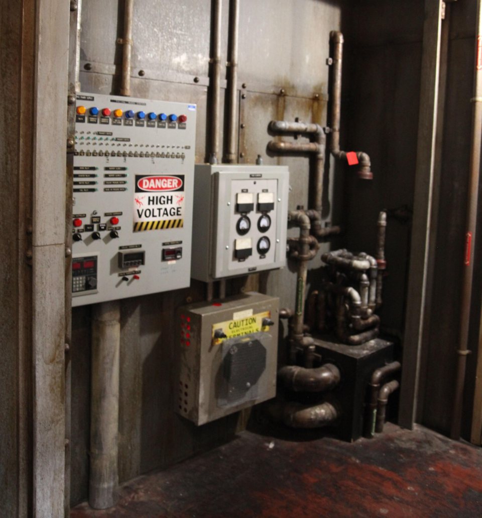 Industrial control panel with a high voltage warning, gauges and rusty pipes