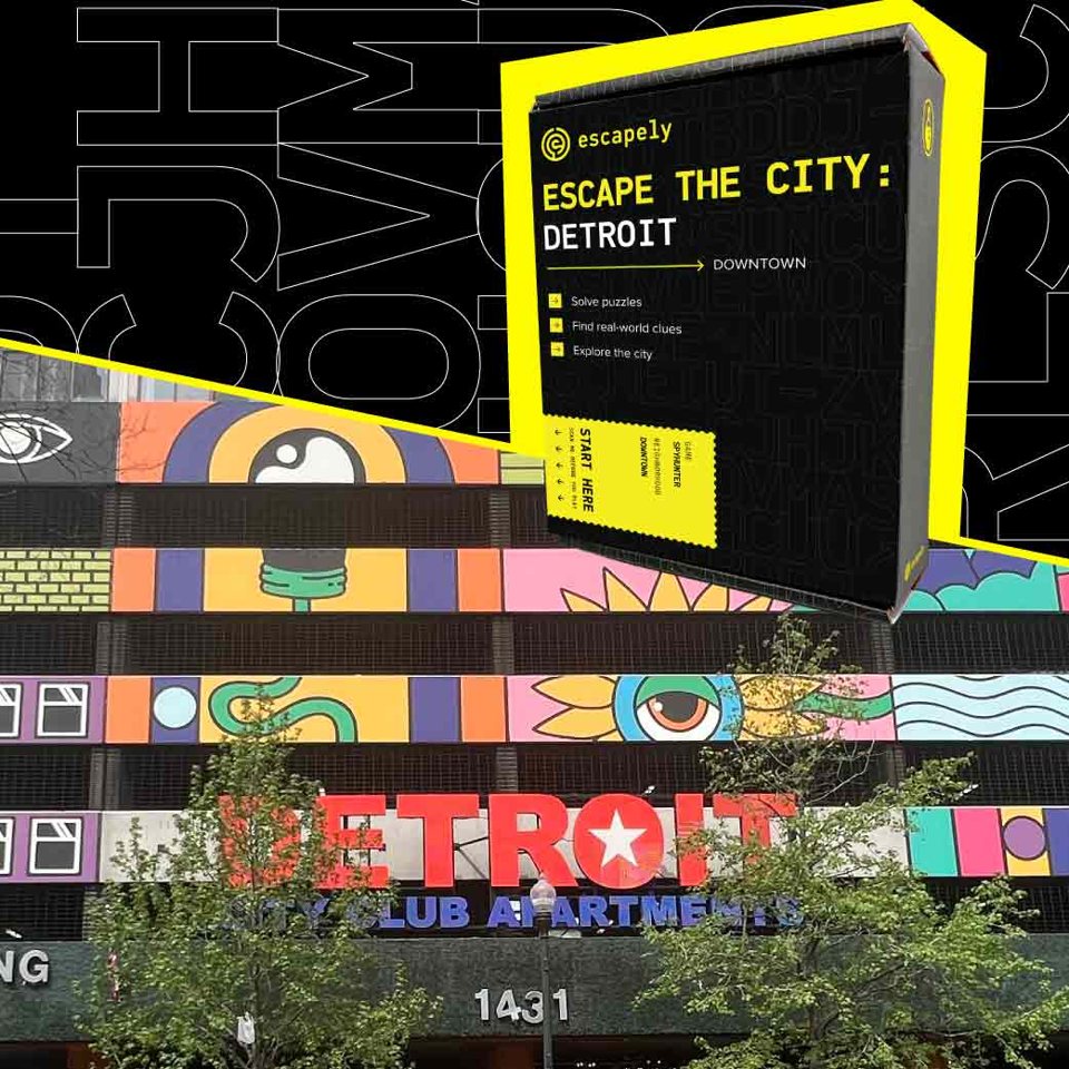 Az Escape the City: Detroit játék doboza a belvárosi City Club Apartments színes falfestménye és piros DETROIT felirata előtt