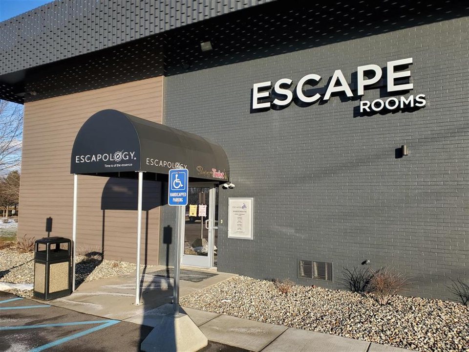 Az Escapology portage-i épülete kívülről, a bejárat fölötti előtetővel és az Escape Rooms felirattal a szürke téglafalon