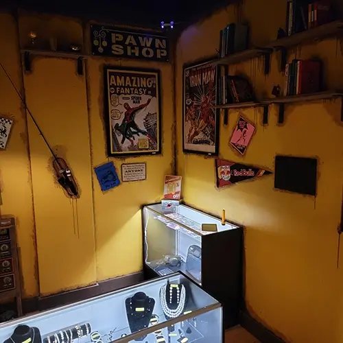 Yellow-walled pawn shop set with comic book posters, bookshelves and a glass jewelry case
