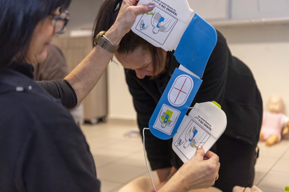 Trainees unfold AED pads to place on a manikin in a CPR and AED class