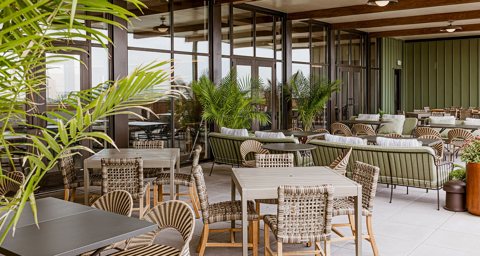 The covered terrace of Topa, the rooftop restaurant, with wicker chairs and palms