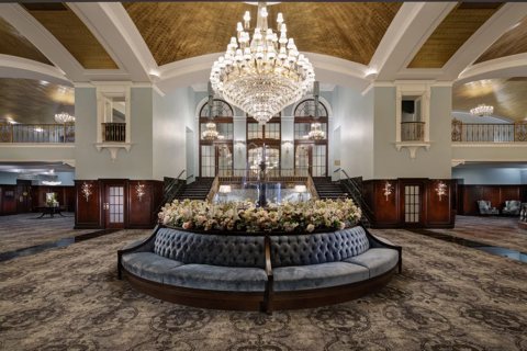 The Pantlind lobby with a crystal chandelier, a round banquette and a gilded ceiling