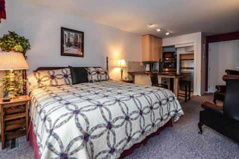 A guest room with a quilted bedspread and wooden furniture