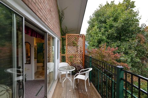 A small balcony with white patio furniture among the trees