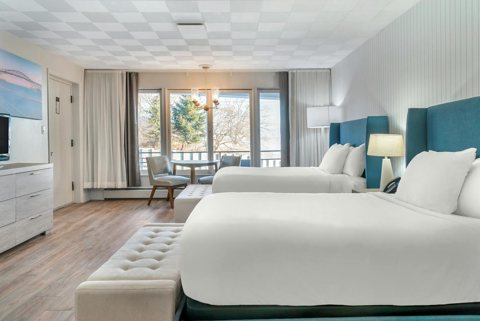 A guest room with two queen beds and teal headboards