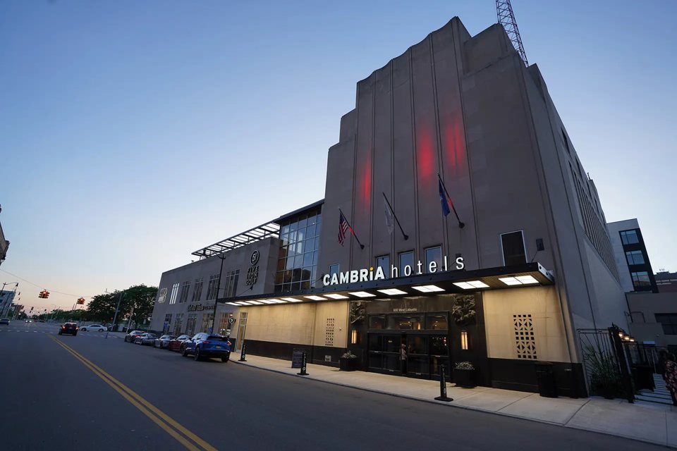 The hotel's Art Deco facade with the Cambria hotels sign at dusk