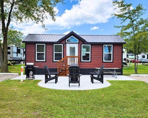 A red cabin with a fire pit and chairs