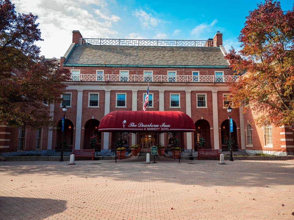 The Dearborn Inn's Georgian-style brick main building with a red awning in autumn