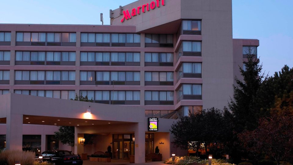 The hotel entrance with its porte-cochère and the red Marriott sign on the facade at dusk