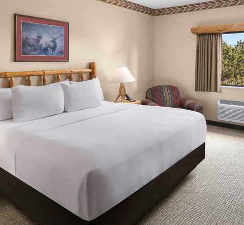 A guest room with a log headboard, a large bed and an armchair