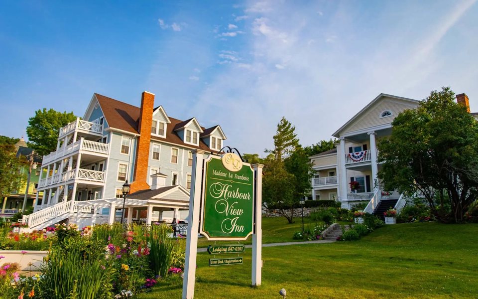 A Harbour View Inn zöld cégére a kék és fehér faházak előtt virágos kertben