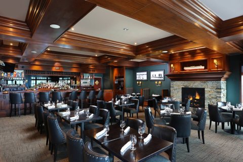 The hotel's dark wood-paneled restaurant with a bar and a stone fireplace