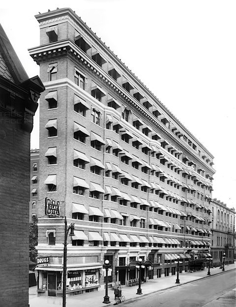 A Henry Clay Hotel, a későbbi Milner Hotel, csíkos ablakponyvákkal és saroktornyos homlokzattal egy 1920-as fekete-fehér képen