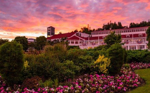 The resort's red-roofed buildings and flower beds under a pink sunset sky