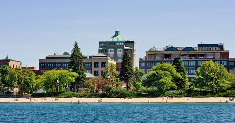 The hotel's green-domed tower above the trees, with a sandy beach and Grand Traverse Bay in front
