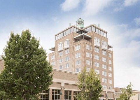 The hotel's light brick tower with bay windows and a green rooftop cupola against a blue sky