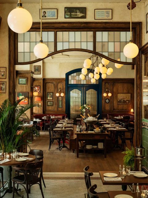 The brasserie on the Book Tower's ground floor with globe lamps, wood panelling and set tables