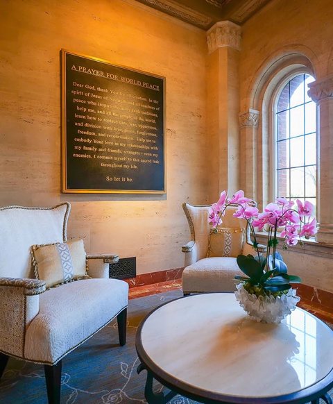 A seating corner with two armchairs, a round table and an orchid beside an arched window