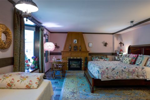 A guest room with a queen bed, a fireplace and a seating corner