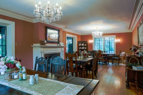 The dining room with crystal chandeliers, a fireplace and wooden tables