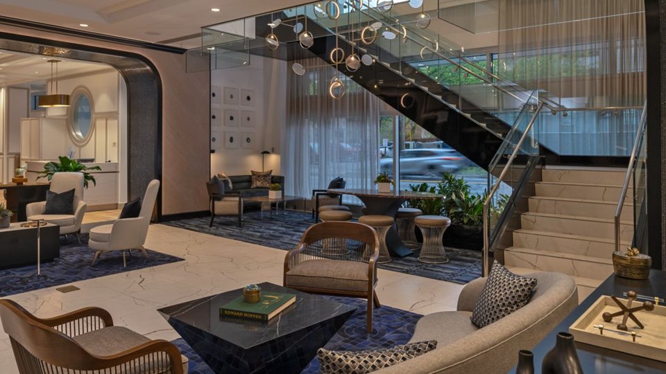 The lobby with lounge seating and a staircase with glass railings