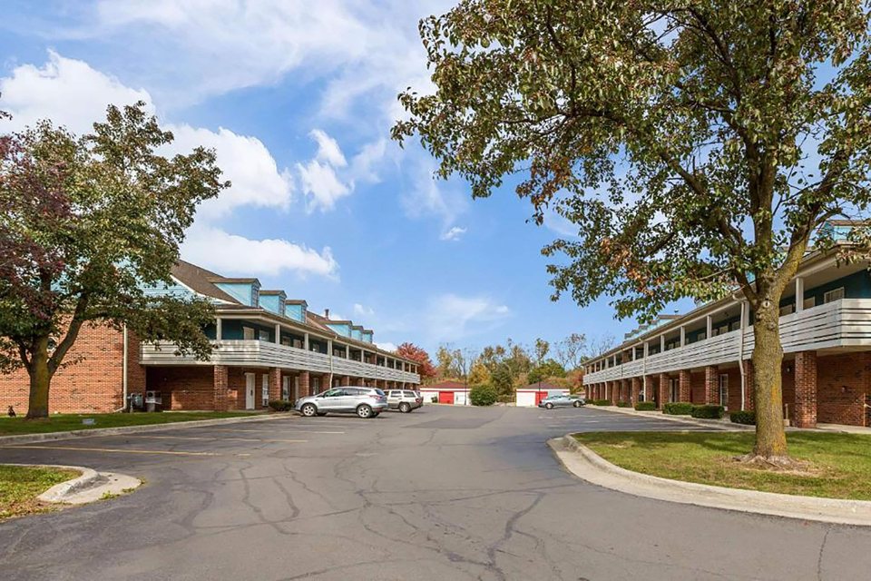The motel's two-storey brick buildings with exterior walkways, trees and parking