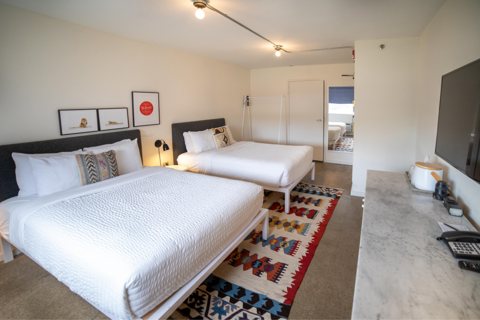 Guest room with two beds in white linens and a patterned rug
