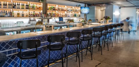 The bar's long counter with a blue tiled front and bar stools