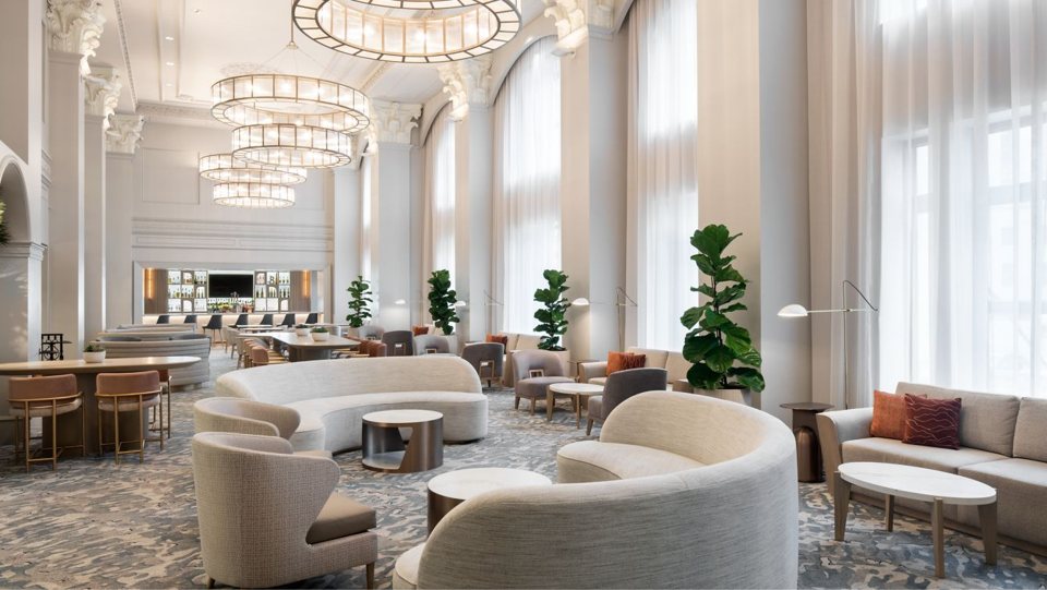 The hotel's bright lobby lounge with curved sofas, chandeliers and tall windows