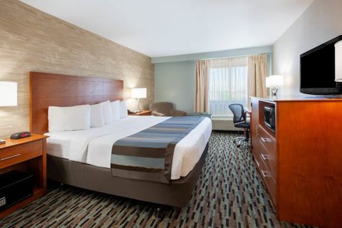 Guest room with a king bed, a striped bed runner and a TV