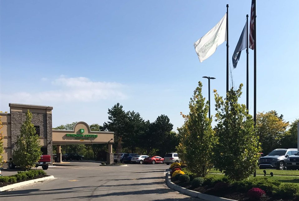 The hotel's entrance canopy, flagpoles and trees next to the parking lot