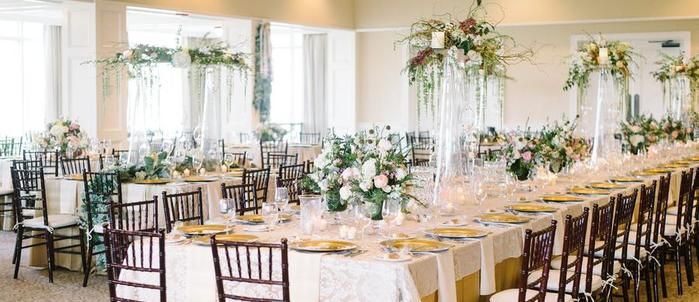 Long wedding reception tables dressed with floral arrangements