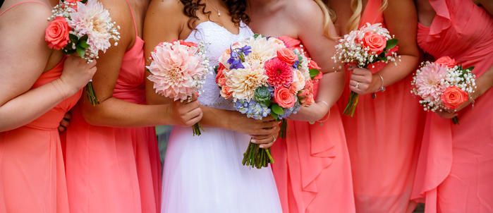 Bridesmaids in coral dresses holding colorful bouquets