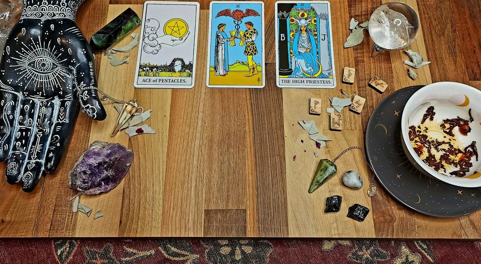Tarot cards, crystals and herbs laid out on a wooden table