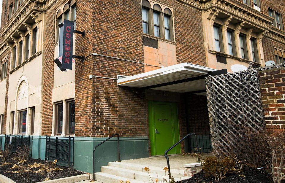 Brick building with a green entrance door and the Common sign