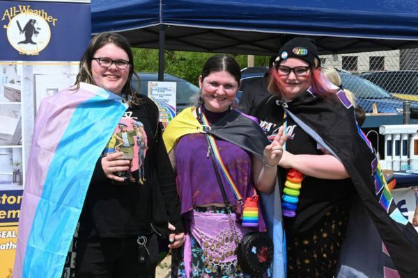 Three friends wrapped in Pride flags at the festival
