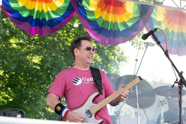 Guitarist performing on a stage decorated with rainbow bunting