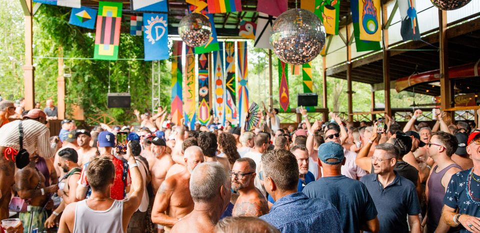 Packed outdoor party under colorful flags and disco balls at The Dunes
