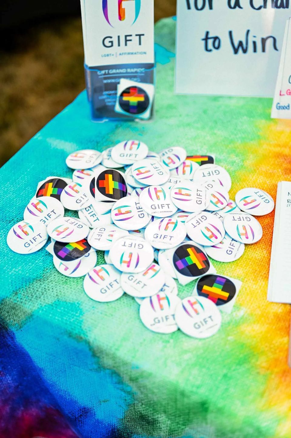 GIFT buttons spread on a rainbow tablecloth at an info table
