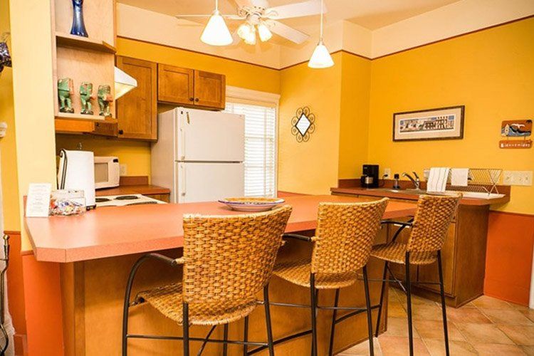 Orange-walled kitchen with wicker bar stools