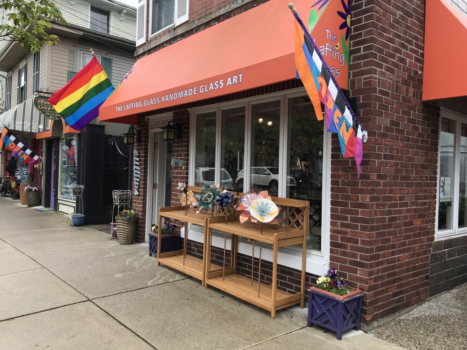 The Laffing Glass storefront with an orange awning and a rainbow flag