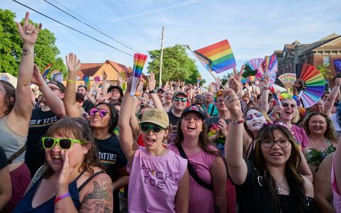 Cheering crowd with rainbow flags and fans at Lansing Pride