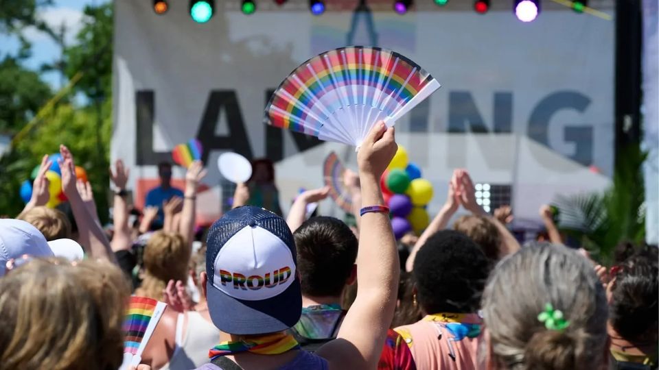Rainbow fan held high in front of the Lansing Pride stage