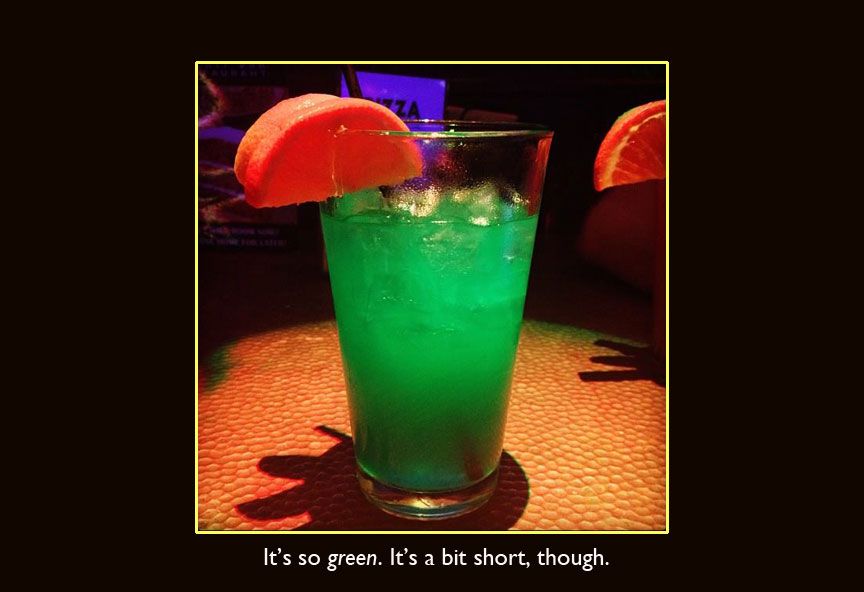 Bright green cocktail with an orange slice at Liberty Bar
