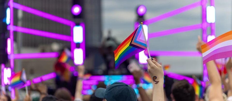 Crowd waving Pride flags in front of the Motor City Pride stage